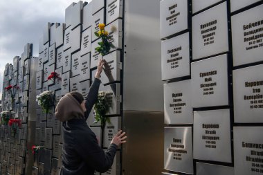 İnsanlar, Rus işgali kurbanlarının anısına 30 Mart 2025 'te, Bucha, Ukrayna' da Rus kuvvetleri tarafından öldürülen sivillerin toplu mezarı yerine çiçek getiriyor. Yüksek kalite fotoğraf