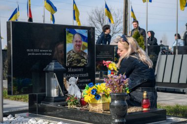 İnsanlar, Bucha 'nın Rus işgalinden kurtuluşunun üçüncü yıldönümünde Kahramanlar Sokağı' na gömülmüş Ukraynalı askerlerin mezarlarına çiçek ve lamba getiriyor. Bucha, Ukrayna, 30 Mart 2025