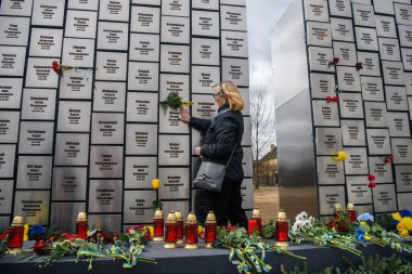 İnsanlar, Rus işgali kurbanlarının anısına 30 Mart 2025 'te, Bucha, Ukrayna' da Rus kuvvetleri tarafından öldürülen sivillerin toplu mezarı yerine çiçek getiriyor. Yüksek kalite fotoğraf