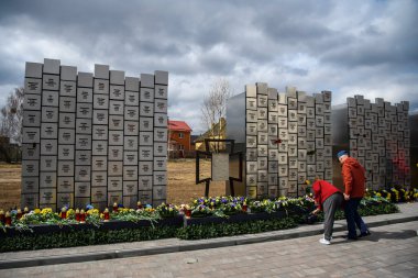 İnsanlar, Rus işgali kurbanlarının anısına 30 Mart 2025 'te, Bucha, Ukrayna' da Rus kuvvetleri tarafından öldürülen sivillerin toplu mezarı yerine çiçek getiriyor. Yüksek kalite fotoğraf