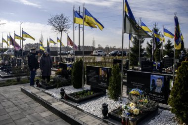 İnsanlar, Bucha 'nın Rus işgalinden kurtuluşunun üçüncü yıldönümünde Kahramanlar Sokağı' na gömülmüş Ukraynalı askerlerin mezarlarına çiçek ve lamba getiriyor. Bucha, Ukrayna, 30 Mart 2025