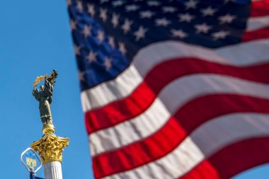 Ukrayna 'nın Kyiv kentindeki Meydan Nezalezhnosti Bağımsızlık Meydanı' ndaki anıtın arka planına karşı Amerikan bayrağı. Yüksek kalite fotoğraf