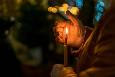 Yaşlı bir kadının elleri kilisede yanan bir mumu tutuyor. Yüksek kalite fotoğraf