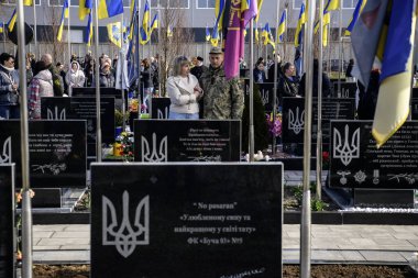 İnsanlar, Bucha 'nın Rus işgalinden kurtuluşunun üçüncü yıldönümünde Kahramanlar Sokağı' na gömülmüş Ukraynalı askerlerin mezarlarına çiçek ve lamba getiriyor. Bucha, Ukrayna, 30 Mart 2025