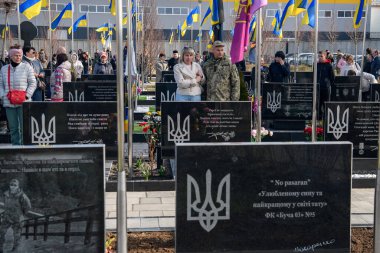 İnsanlar, Bucha 'nın Rus işgalinden kurtuluşunun üçüncü yıldönümünde Kahramanlar Sokağı' na gömülmüş Ukraynalı askerlerin mezarlarına çiçek ve lamba getiriyor. Bucha, Ukrayna, 30 Mart 2025