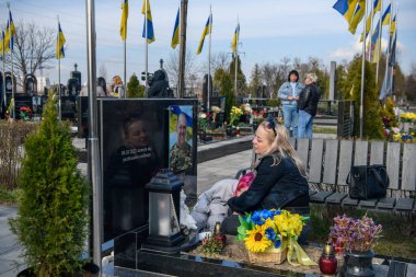 İnsanlar, Bucha 'nın Rus işgalinden kurtuluşunun üçüncü yıldönümünde Kahramanlar Sokağı' na gömülmüş Ukraynalı askerlerin mezarlarına çiçek ve lamba getiriyor. Bucha, Ukrayna, 30 Mart 2025