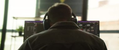 Bir birey, modern ve verimli bir çalışma alanında çift monitör kullanırken görevlerine derin bir şekilde dalmıştır.