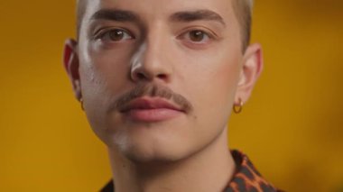 Kapalı alanda kameraya gülümseyen bıyıklı genç homoseksüel adamın yakın plan yüzü.