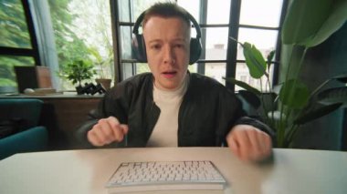 Kulaklıklı komik bir genç adam bilgisayarla çalışıyor müzik dinliyor ve dans ediyor. Pozitif iş adamının portresi