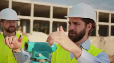 Şirket başkanı işçilerle proje hakkında tartışıyor ve ölçüm için teodolit anket aletini kullanıyor. Gün ışığında ayakta duran grup mühendisleri. İnşaat şirketi