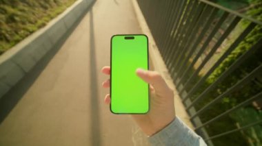 Güneşli bir günde erkeğin cep telefonunu dikey pozisyonda tutarken çekilmiş yatay görüntüler. Beyaz adamın kaldırımda yürürken akıllı telefon kullandığına dair bir görüntü. Dışarıda.