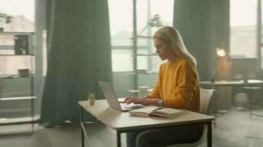 Dizüstü bilgisayarda yazan harika iş kadını gülümseyip ofiste dans ederken mutlu oluyor. İşle ilgili haberler iyi. Kamera hareket ediyor. 360 derece