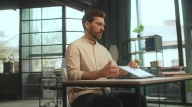 Kapalı dizüstü bilgisayarda oturan gülümseyen adam ofiste mutlu ve düşünceli. İş günü kameranın hareket etmesi sona erdi. 360 Derece