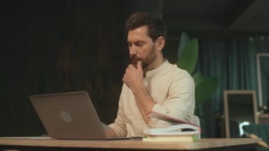 Masada oturan iş adamı dizüstü bilgisayar kağıdı kullanıyor. Ofiste ciddi görünüyor. Mesai saati. Kamera hareket ediyor. 360 Derece