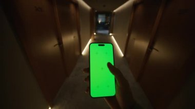 Tanımlanamayan beyaz bir gencin yeşil ekranlı cep telefonu kullanmasının görüntüsü. Otelin karanlık koridorunda yürürken elinde akıllı telefon olan bir adamın fotoğrafı. İçeride. Model