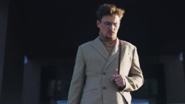 Gözlüklü ciddi bir genç adam güneş ışığı şehrinde bir gölün yakınında yürür. İş adamı. Şık bir adam. Yavaş çekim