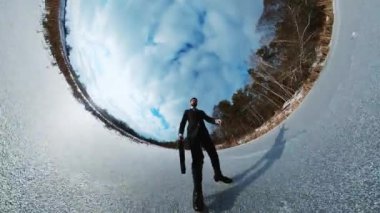 Toplantıya giderken siyah takım elbiseli bir iş adamının donmuş asfaltta buz pateni yaptığını gösteren 360 derecelik bir video. Bavullu genç adam işe gidiyor. Kış ormanı ve açık gökyüzü