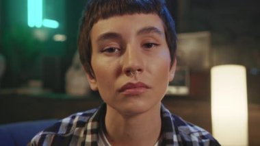 Kahverengi gözlü, kısa saç kesimli, kendine güvenen genç bir kadının akşam vakti kameraya doğrudan bakışını yakından çek. Burun halkalı hippi kız. 20 'likler