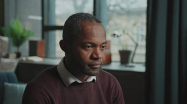 Meşgul bir Afrikalı Amerikalı adamın videosu bilgisayarın başında oturup ekrana bakmaya odaklandı. Çatı katının bulanık arka planında kameraya gülümseyen iş adamının portresi