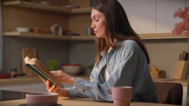 Odaklanmış genç bayan okuyucu el ele kitap tutuyor ve evde yalnız başına sakin bir anın tadını çıkarıyor. Mutfakta klasik edebiyat okuyan zarif bir bayan. Huzurlu atmosfer