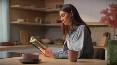 Şık giyinmiş şık bir esmer, mutfakta oturmuş kitap okuyor. Odaklanmış genç bir kadın yalnız zaman geçiriyor. Sabah rutini. Kendine zaman ayır. Kapalı