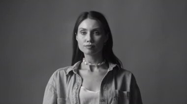 Siyah ve beyaz kadın, stüdyoda tek renkli bir arka planda başlarını dikmiş kameraya bakıyor. Ciddi kız portresi