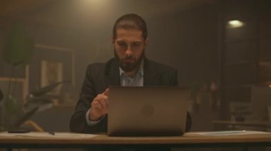 Çekici bir iş adamının portresi masa başında çalışıyor. Gece ofisindeki bilgisayarı kullan. İşine odaklan. Akşam ışığı