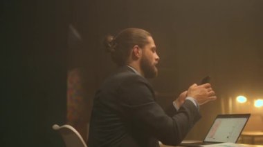 Gece ofisindeki kızgın işadamı masa başında oturup evrak işleriyle kafayı bozmuş ve stresli hissediyor. Telefonda gergin konuş.