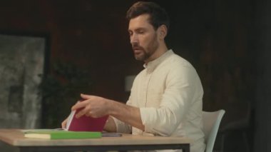 Not defteriyle masa başında oturan genç bir adamın portresi. Telefonla sosyal medya sohbeti. 360 derece. Kamera hareket ediyor