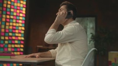 Kamera etrafta dolanıyor. Masada oturan adam telefonda konuşuyor. Gülümseyerek mutlu olun. Modern ofis. 360 Derece