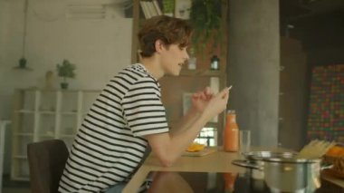 Dost canlısı beyaz adamın yemek masasında meyve ve sebzelerle oturduğunu gösteren hareketli görüntüler. Sarı akıllı telefon tutan ve sosyal güvenlik numaralarını karıştıran adam.