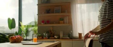 Yemek odasında dizüstü bilgisayarla oturan çizgili tişört giyen hoş beyaz bir adamın yatay görüntüleri. Adam sabah bilgisayarda çalışmaya başlıyor. Samimi mutfak. Parallaks etkisi. 360 derece çekim