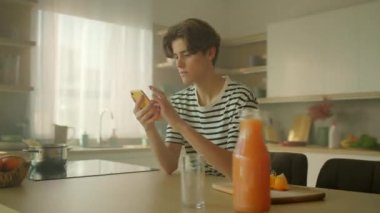 360 derece izleme mutfağı. Yemek masasında otururken akıllı telefon kullanan yakışıklı, beyaz bir adamın fotoğrafı. Kamera hareket ediyor. Parallaks etkisi. Sinematik efekt