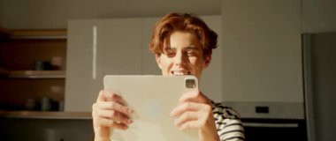 360 derece mutfak. Yakışıklı, kızıl, yakışıklı, beyaz bir adamın dijital tablet ekranına bakıp gülümsediği bir görüntü. Modern stüdyoda aletleri elinde tutan mutlu adam. Bildirim