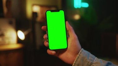 Eller kapalı alanda dikey yeşil ekranlı cep telefonu tutuyor ve kullanıyor. Sosyal medya. Model