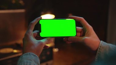 Kapalı alanda yatay yeşil ekranı olan bir cep telefonunda daktilo kullanarak ellerini kapat. Sosyal medya. Akıllı telefonmuş. Model