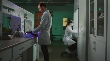 Laboratuvarda gözlüklü iki genç bilim adamı birlikte çalışıyor. Tıp, biyoteknoloji, kimya. Eczacılık. Deneysel