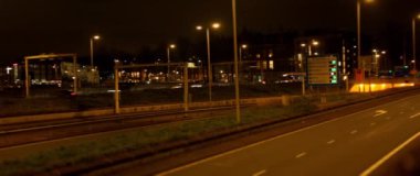 Gece yarısı hareketli bir şehir aydınlık sokaklar ve gece gökyüzüne karşı yüksek binalar.