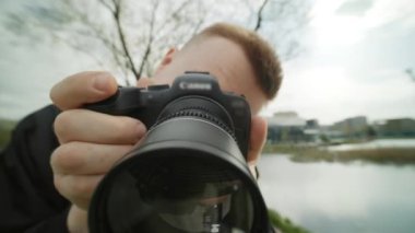 Şu anda bir adam Canon kamerasıyla yüksek kaliteli bir fotoğraf çekiyor ve bu aletle bir fotoğrafçı olarak yeteneklerini gösteriyor.