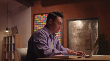 Dizüstü bilgisayar kullanan Asyalı çekici bir iş adamı. Geceleri ekrana ciddi ciddi bak. Evden çalışıyorum. 360 derece. Etrafta dolanıyorum.