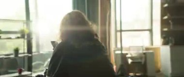 Şık gözlükler takan genç bir adam, şık ve modern bir çalışma ortamı içinde akıllı telefonunu kullanıyor.