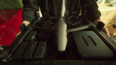 Bir birey, medya depolama ortamında gerekli aksesuarlarla birlikte kompakt bir drone düzeneği tutuyor