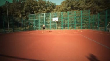 Genç bir insan, çevresini çevreleyen parlak yeşil çitlerle çevrili canlı kırmızı bir spor salonunda enerjik bir şekilde koşar.