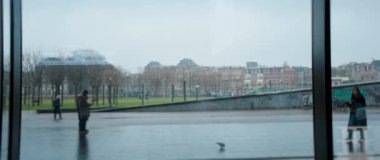 Amsterdam 'da sakin bir şehir manzarası, yağmurlu bir günde yansıtıcı bir yüzeyden yansıyor..