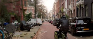 Çekici ve pitoresk bir sokak sahnesi park etmiş arabaları, bisikletleri ve canlı sonbahar yeşilliklerini sergiliyor.