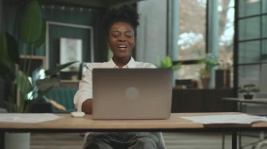 Happy African American business woman sitting on chair use laptop in office. Smiling. Camera moving around. 360 degrees