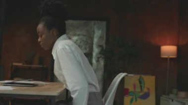 Ofiste çalışan Afro-Amerikan bir kadın sandalyeye oturmuş dizüstü bilgisayar başında çalışıyor. Gülümseyen mutlu hisseder. Kamera hareket ediyor. 360 derece