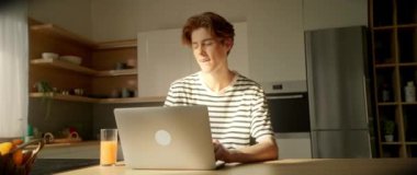 Çekici, düşünceli, beyaz bir adamın dizüstü bilgisayarda oturup klavyede daktilo çalması. Mutfakta sosyal medyada konuşan dalgın bir adam. Parallaks etkisi. Kamera hareket ediyor