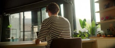 Masada oturan ve dizüstü bilgisayara bakan genç beyaz bir adamın hareketli görüntülerini izliyorum. Mutfaktaki klavyede şık gömlekli düşünceli bir adam daktilo kullanıyor. Parallaks etkisi