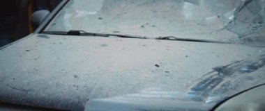 Bombardımandan sonra toza bulanmış ön camı kırılmış bir araba görüntüsü. Bozuk bir sivil arabası. - Savaş. Otomobil sigortası. Hasar